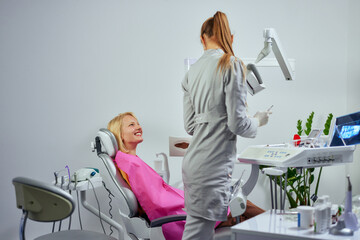 Wall Mural - Female dentist examining the teeth of a young woman