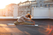 Young Sporty Happy Mixed-race Woman Doing Stretching Exercises On Yoga Mat On House Roof In Morning