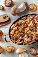 Mushroom beef stroganoff, a casserole of boletus, champignons, and meat, overhead flat lay shot with ingredients, on a rustic wooden background