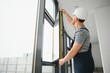 © Serhii - Construction worker repairing plastic window with screwdriver indoors, space for text. Banner design