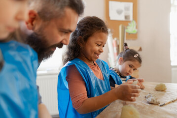 Wall Mural - Group of little kids with teacher working with pottery clay during creative art and craft class at school.