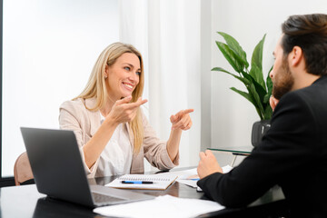  Going over details. Male and female confident business people discussing something while spending time in the office. Male office worker looking at his colleague while discussing something