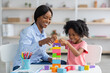 © Prostock-studio - Adorable black kid and child development specialist playing with bricks