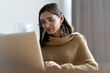 © opolja - Smiling woman with laptop in home office.