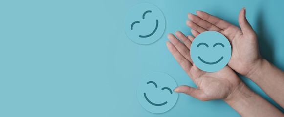 Wall Mural - Hand holding blue paper cut happy smile face, positive thinking, mental health assessment , world mental health day concept	