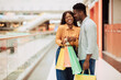 © Prostock-studio - Portrait of black couple with shopping bags kissing in mall