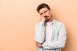 © Asier - Young caucasian man isolated on beige background who feels sad and pensive, looking at copy space.