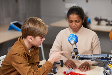 Wall Mural - Two teenage kids building electric robots while enjoying engineering class in school, copy space