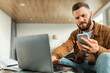 © Prostock-studio - Serious Freelancer Man Using Phone And Laptop At Home