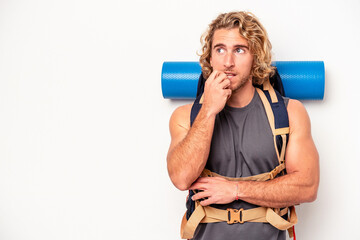 Wall Mural - Young mountaineer caucasian man with a big backpack isolated on white background relaxed thinking about something looking at a copy space.