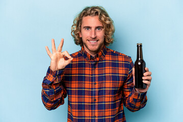 Wall Mural - Young caucasian man holding beer isolated on white background cheerful and confident showing ok gesture.