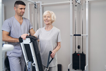 Wall Mural - Pensioner holding cable pulley weight machine handle in hand