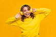 © mary_markevich - smiling attractive woman listening to music in headphones on yellow background