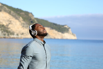 Man with black skin meditating on the beach with headset