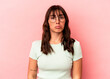 Young Argentinian woman isolated on pink background sad, serious face, feeling miserable and displeased.