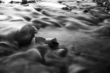 River water flowing trough the stones long exposure silky water effect black and white