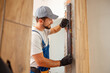 © Kostiantyn - Craftsman, male worker in uniform using bubble level while measuring the wall indoors