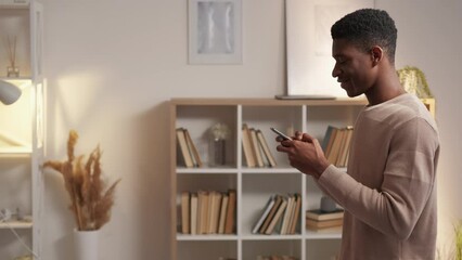 Mobile network. Digital communication. Gadget leisure. Happy millennial man texting online chat message on phone social media browsing internet at home empty space.