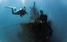 Two Divers Exploring The Sattakut Wreck Off The Coast Of Koh Tao