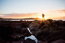 A Man Stands In Front Of The Sunset At Low Tide