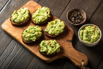 Wall Mural - Sandwiches with guacamole sauce on a cutting board over old wooden background.
