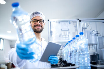 Working in bottling water factory and production line worker checking quality of beverage and plastic packaging.