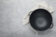 Empty iron wok and towel on grey table, top view. Space for text