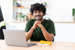 © kucherav - Portrait of a successful young Indian male freelance using laptop and looks at the camera, remote work from home, online education