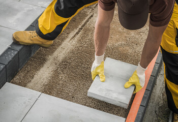 Wall Mural - Worker Building Large Concrete Bricks Garden Path