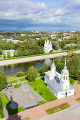 Rooftop view of the old town from the Saint Sophia bell tower in Vologda, Russia. Blue sky with clouds, green trees and grass, white church walls and towers, silver domes with orthodox crosses, river