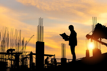 Silhouette of Engineer and workers checking project at building site, worker team at construction site sunset in evening time