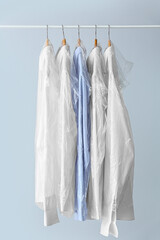 Wall Mural - Rack with clean shirts in plastic bags on grey background