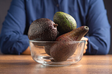 Wall Mural - Close-up of fresh avocados in a glass bowl on a wooden table.