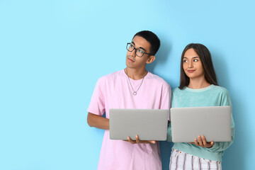 Young couple with laptops on blue background