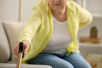 Sticker - Senior woman with back pain taking walking stick at home, closeup