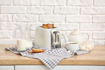 white toaster with bread slices and drinks on table near brick wall