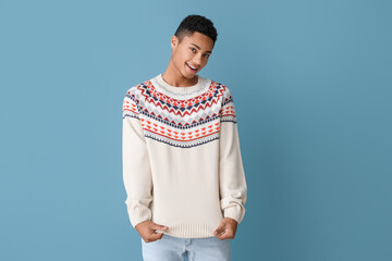 Wall Mural - Handsome African-American guy in knitted sweater on color background