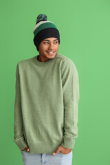 Wall Mural - Handsome African-American guy in knitted sweater on color background