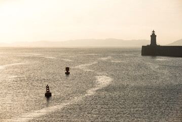 Wall Mural - Lighthouse in St Peter Port Harbour at sunrise, Guernsey, Channel Islands, United Kingdom, seascape background with copy space