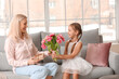 © Pixel-Shot - Little girl greeting her grandmother with tulips at home on International Women's Day