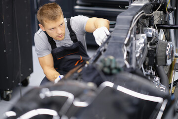 Wall Mural - Concentrated serious handyman with tool fix damaged motorbike in garage