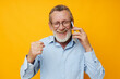 © Tatiana - Senior grey-haired man gray beard with glasses talking on the phone isolated background