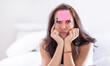 Woman who forgot something has pink postit on her forehead holding her head with both heads, thinking hard