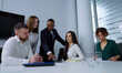 © yk_stock - Diverse team of managers gathering around table and discussing company progress, Black man showing something on tablet. Employees brainstorming at meeting. Concept of business