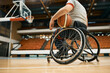 Wheelchair-bound basketball player holding a ball during sports training.