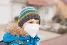 Kid Boy Wearing Ffp Medical Mask On The Way To School. Child Backpack Satchel. Schoolkid On Cold Autumn Or Winter Day With Warm Clothes. Lockdown And Quarantine Time During Corona Pandemic Disease