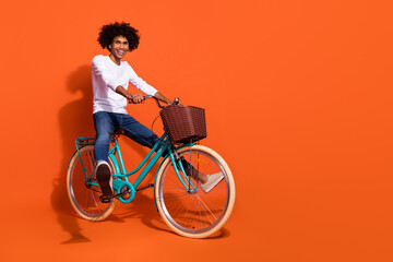 Wall Mural - Photo of cool fooling guy wear white shirt driving fast cycle empty space isolated orange color background