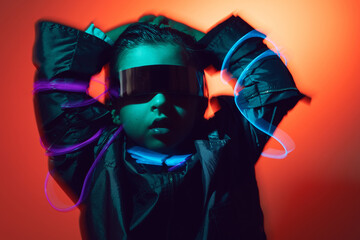 Wall Mural - blur portrait cyberpunk boy child in vr glasses in blue and red tones with wires on a red background