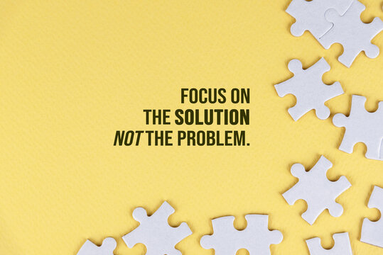 Wall Mural -  - Motivational quote - Focus on the solution not the problem. With white jigsaw puzzle background on soft yellow background. Life and business solution concept.