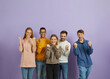 © Studio Romantic - Victory and achievement. Happy positive young multiracial men and women rejoice together on purple background. Joyful people in casual clothes happily clench their fists looking at camera. Banner.